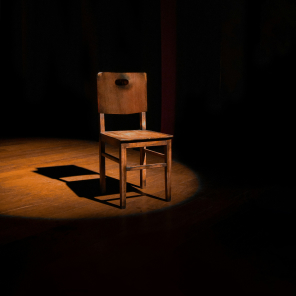 Chaise en bois éclairée par un projecteur, ambiance de scène