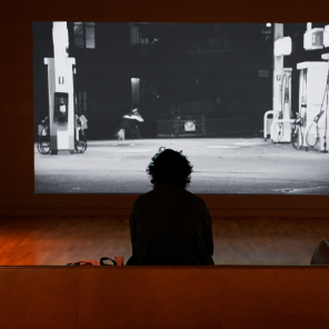Personne regardant une projection vidéo d'une station-service la nuit.