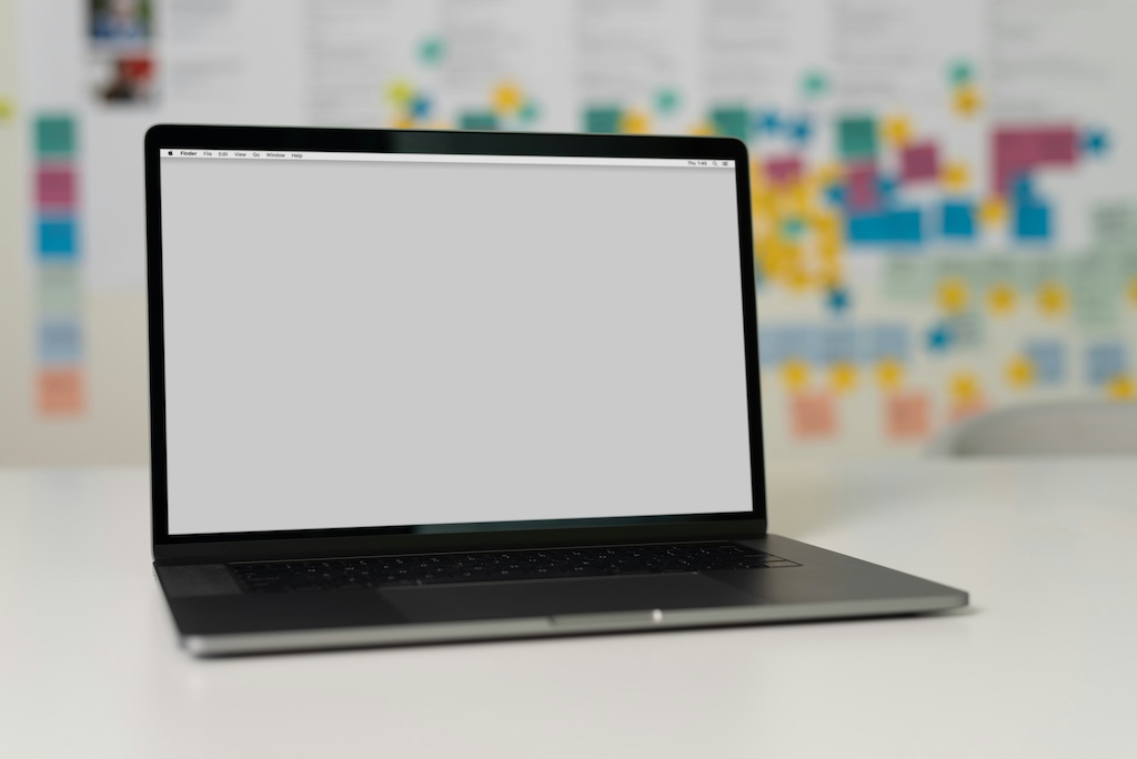 Ordinateur portable ouvert sur un bureau blanc, arrière-plan flou de tableau d'organisation