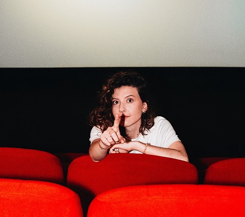 Consultante en expérience client, femme aux cheveux bouclés dans une salle de cinéma.