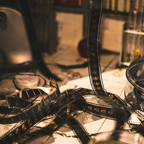 Bandes de pellicule de film anciennes sur un bureau, évoquant l'histoire du cinéma.