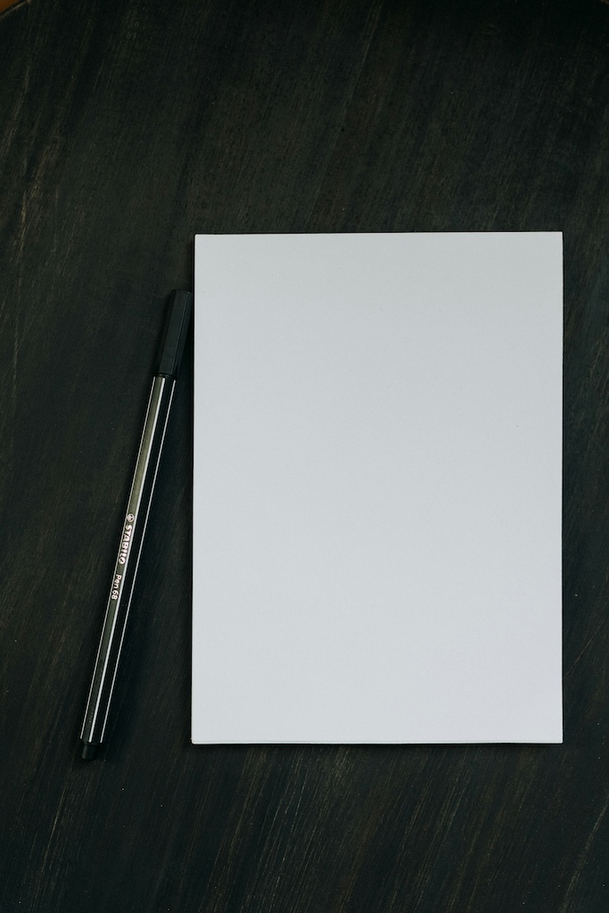 Feuille blanche et stylo noir sur fond sombre